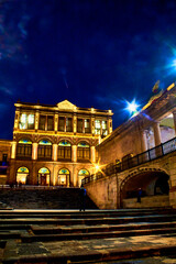 Fototapeta na wymiar stairs in street of downtown center at night, buildings with golden lights in zacatecas, mexico 
