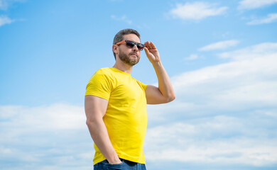man in yellow shirt and glasses outdoor on sky background