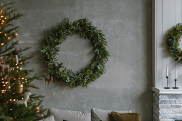 Beautiful huge wreath on the wall in loft apartment decorated for winter holidays. Copy space. Minimal aesthetic holiday decoration.