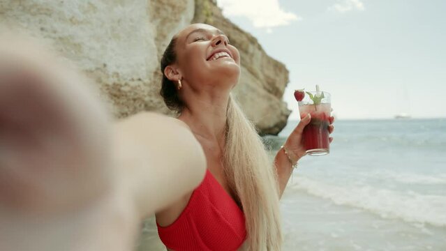 Young European woman in bikini on the beach in summer. Girl using her smartphone. Taking photos, selfie. Cinematic 4K
