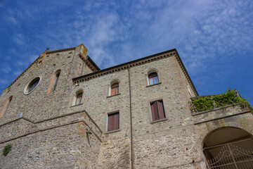Fototapeta na wymiar Ancient stone building against the blue sky with white clouds. Arquà Petrarca, Italy.