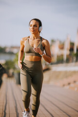 Active young beautiful woman running on the promenade along the riverside © BGStock72