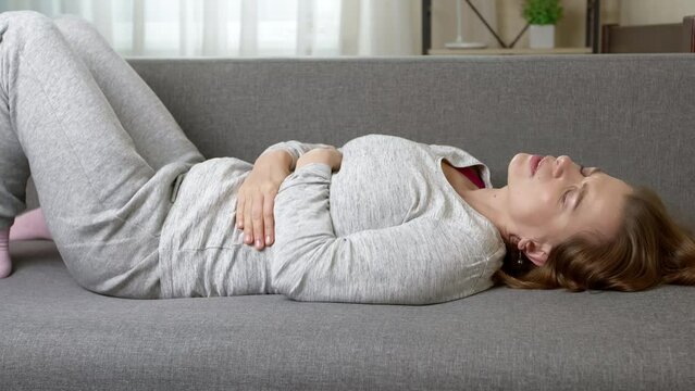 Pain in the abdomen lying on the couch. Menstrual cycle, period. Diarrhea concept.