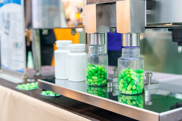 close up transparent plastic bottle under nozzle dispenser component of automatic medicine capsule bottle filling and counting machine during manufacturing process - Powered by Adobe