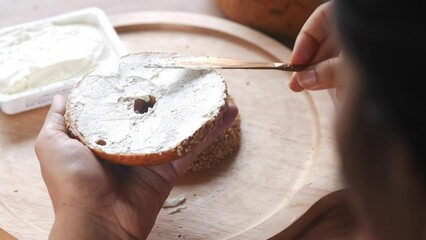 women cheese cream spread on fresh bagel bread 