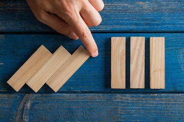 Falling wooden dominos being interrupted by male hand in a conceptual image of crisis management