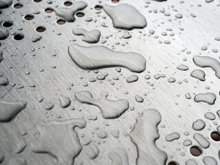 Rain drops close up photo on a polished metal surface of a bench