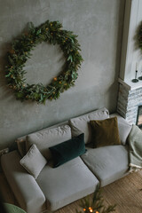 Beautiful Christmas wreath on the wall in cozy living room. Scandinavian style, aesthetic holiday decor.