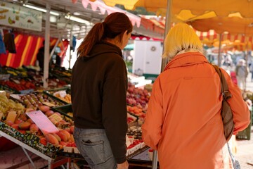 Closeup of a young woman advising the customer at a vegetable stall at a farmers market