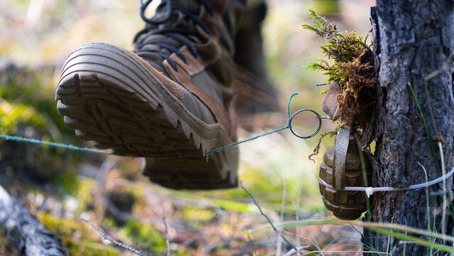 Soldier steps on a mine trap. The soldier's boot rips off the wire and rips off the pin of the grenade.
