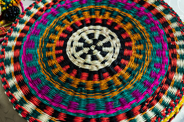 Wicker placemats made from Paja toquilla straw, which is a vegetable fiber dyed in various colors. Craft market in Cuenca, Ecuador