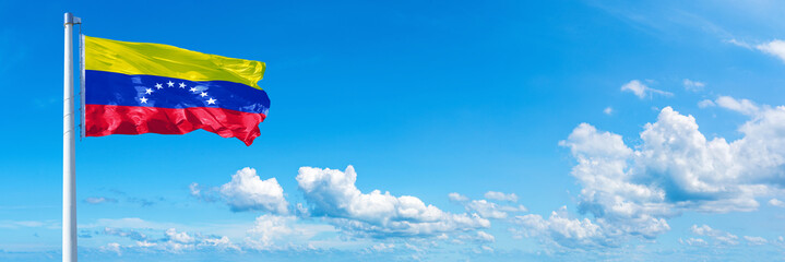 Venezuela flag waving on a blue sky in beautiful clouds - Horizontal banner