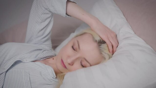 worried blonde woman lies in bed on a pillow, can't sleep