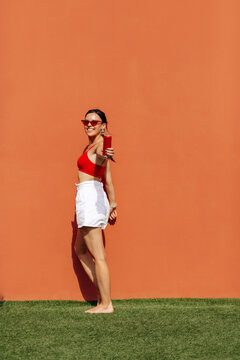 A girl on an orange background with a red tin can in her hands. Cheerful girl, advertising shooting