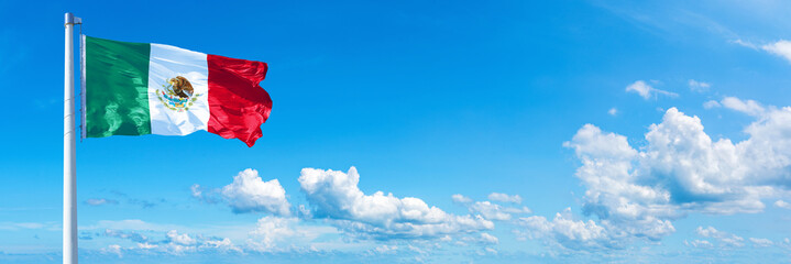 Mexico flag waving on a blue sky in beautiful clouds - Horizontal banner