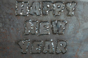 A stern happy new year phrase made from steel letters welded to a steel sheet. Unusual New Year's card