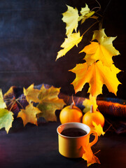 a yellow mug of hot tea or coffee on a wooden table. Maple branch with yellow leaves, small pumpkins. Thanksgiving greeting card