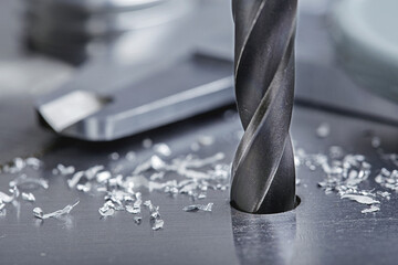metal drill bit make holes in steel billet on industrial drilling machine with shavings. Metal work...