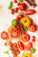 Selection of organic large heirloom and cherry tomatoes on white cream brown concrete background, selective focus