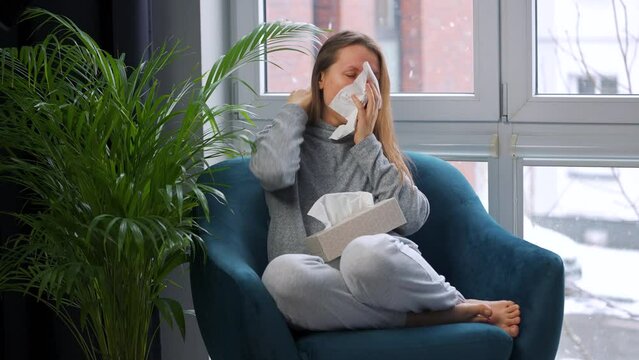 Unhealthy woman sits in a chair and coughs because she has a cold, flu