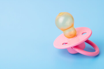 Orthodontic pacifier on a blue background. Pink baby pacifier