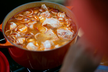 Tom yam nam khon soup in a vintage large cast iron enamel pan, close-up, top view