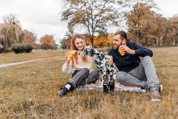 A young couple is having fun with a Dalmatian dog outdoors.