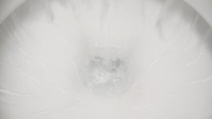 The camera plunges into the toilet while the water is flushed there. Dolly slider extreme close-up.