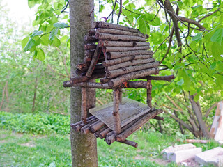 Bird feeder made of wooden sticks and hanging on a tree