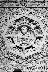 Black and white photo showing in close-up church stone wall in Pisa extensively carved with religious symbols