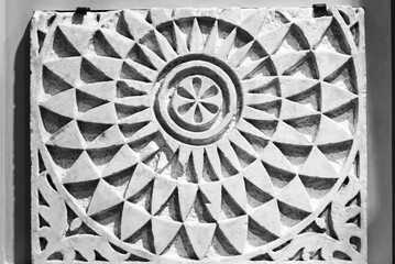 Black and white photo showing in close-up piece of ancient marble wall decorated with a mandala...