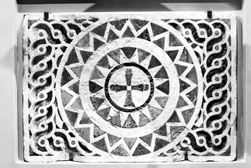 Black and white photo showing in close-up piece of ancient wall decorated with a mandala pattern...