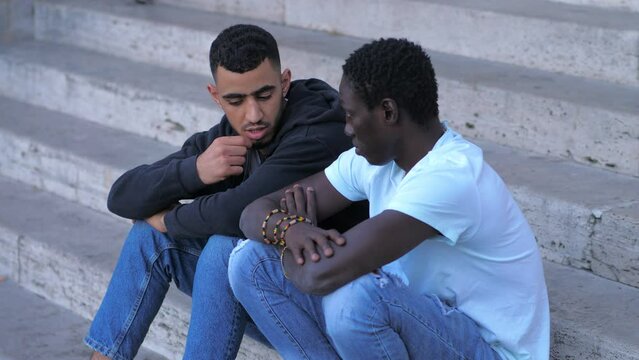 Tunisian man comforting a sad african man mourning on the stairs