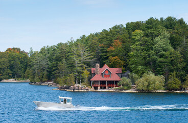 Aluminum boat driving past a large upscale cottage