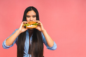 Young beautiful asian japanese chinese woman eating sandwich or big burger with satisfaction. Girl...