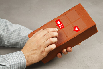 Hands hold brick instead of smartphone and scrolling pictures with likes, concept there is no...