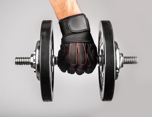 Hand in workout glove holding heavy barbell closeup. Bodybuilding concept