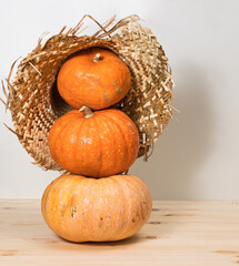 Pyramid of three yellow pumpkins in a straw hat, golden autumn, Halloween concept and autumn harvest of pumpkins