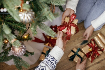 Family exchanging christmas gifts under christmas tree in festive decorated room close up. Merry...