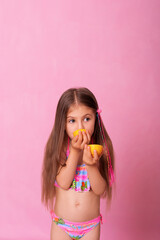 Caucasian beautiful little girl with fresh yellow lemons on a pink background. Little girl with lemon. Funny child isolated on pink.