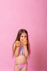 Caucasian beautiful little girl with fresh yellow lemons on a pink background. Little girl with lemon. Funny child isolated on pink.