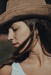 cowboy girl with hat looking to one side on a sunny day