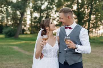 Young man groom hugging young woman bride, holding glasses of wine, meeting eyes. Relationship,...