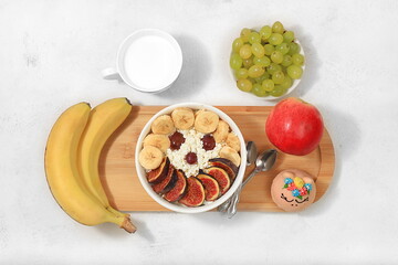 Healthy breakfast with ingredients, fun food for kids. Cottage cheese with figs and bananas, apples and grapes, top view, Healthy and natural food concept.