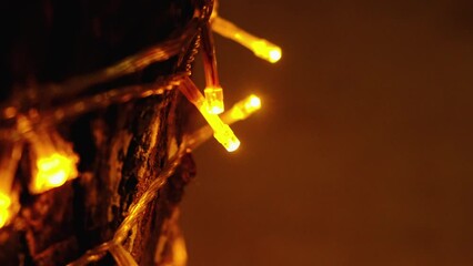 Close-up defocused lights on wood texture. Warm light of garland lights in twilight. Cozy home winter evening vibes. Scandinavian decor. Comfy moments of family christmas holidays. Hygge brown palette