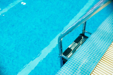 Pool ladder with stairs in empty pool for sport swimming training in leisure center.Ladder stainless handrails for descent into swimming pool. Swimming pool with handrail .