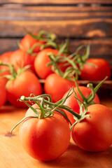 Tomatoes, beautiful details of fresh red tomatoes on branches over rustic wood, selective focus.