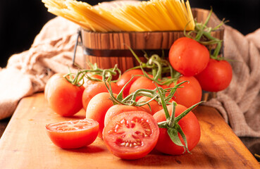 Pasta, beautiful details of red tomatoes and strands of raw spaghetti over rustic wood, selective focus.
