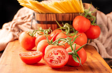 Pasta, beautiful details of red tomatoes and strands of raw spaghetti over rustic wood, selective focus.