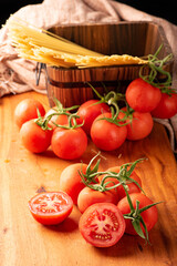 Pasta, beautiful details of red tomatoes and strands of raw spaghetti over rustic wood, selective focus.